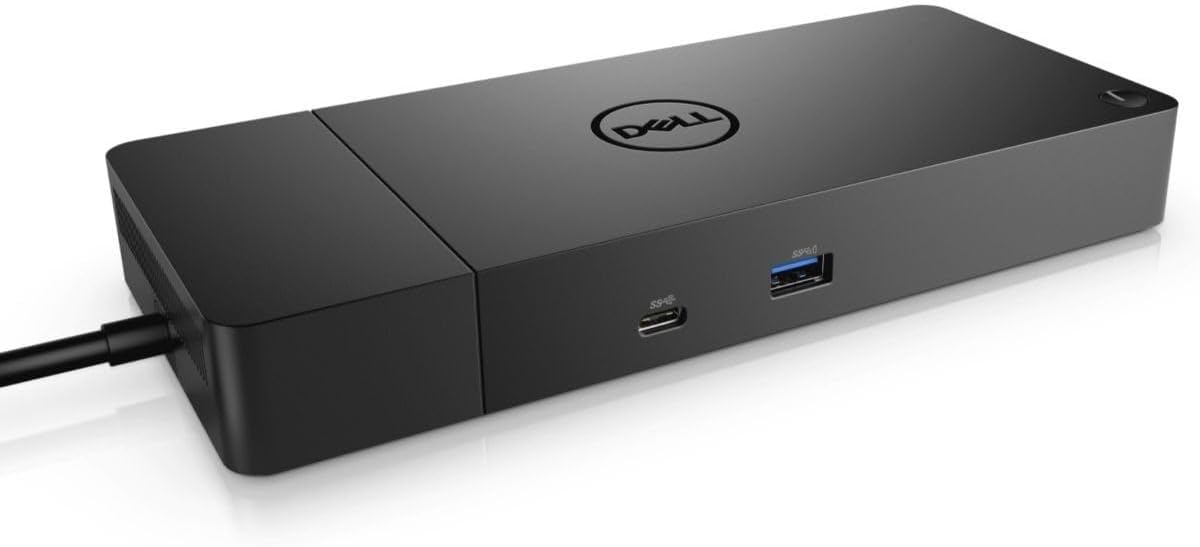 The Dell WD19S 180W Docking Station sitting on a compact wooden desk inside a modern camper van, connected to a laptop and an external monitor with a forest view in the background.