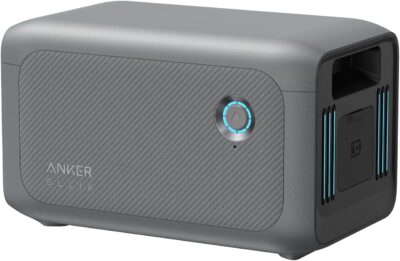 Anker SOLIX BP1000 expansion battery stacked underneath an Anker SOLIX C1000 power station with a connecting cable in a camping environment.