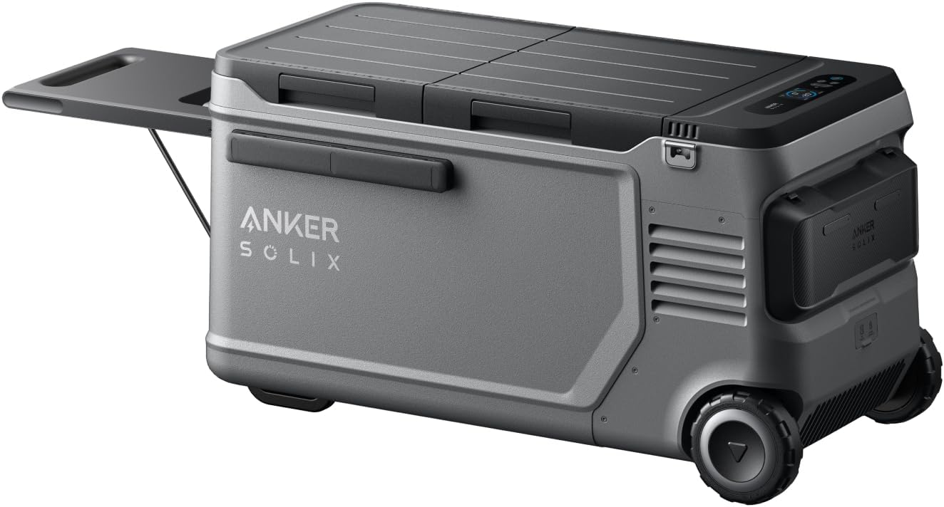 Anker SOLIX EverFrost 2 58L electric cooler with wheels and telescopic handle standing on a grassy campsite next to a solar panel.