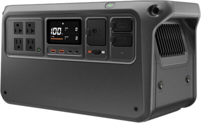 DJI Power 1000 V2 Portable Power Station in a modern campsite setting powering a coffee machine and drone batteries.