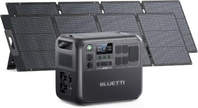 The BLUETTI AC200L solar generator with two 200W solar panels deployed on a sunny campsite next to a modern camper van.