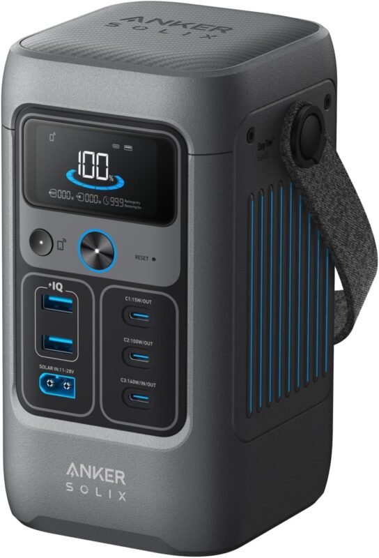 Anker SOLIX C200 DC portable power station sitting on a camping table charging a smartphone and a laptop via USB-C