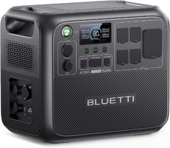BLUETTI AC200L portable power station showing the front ports and 30A RV outlet on a camping table in front of a modern travel trailer.
