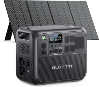 The BLUETTI AC200L solar generator with its 350W solar panel deployed in a sunny campsite next to a modern camper van.